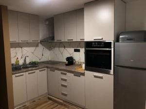 a kitchen with white cabinets and a black appliance at Blue apartman in Belgrade