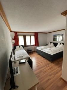 a room with two beds and a table and a desk at Hotel Alpha Thun in Thun