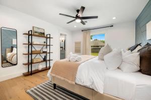 1 dormitorio con cama blanca y ventilador de techo en Osage Oasis-Bikes Available-1 Block to Trails, en Bentonville