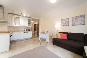 ein Wohnzimmer mit einer schwarzen Couch und einer Küche in der Unterkunft Beautiful Flat with heated pool near the beach in Arguineguín