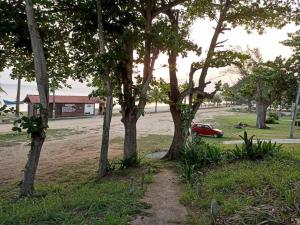 um carro vermelho estacionado ao lado de árvores num campo em Casa 4 quartos, 2 suítes c/ acessibilidade em São Pedro da Aldeia