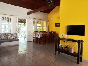 uma sala de estar com uma mesa e uma parede amarela em Casa 4 quartos, 2 suítes c/ acessibilidade em São Pedro da Aldeia