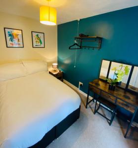 a bedroom with a white bed and a desk with a bed sidx sidx at Mount Pleasant Retreat in Troed-y-rhiw