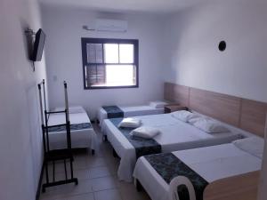 um quarto com três camas e uma janela em Golfinho Plaza Hotel em Cananeia