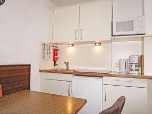 Una cocina con gabinetes blancos y una mesa de madera. en Apartment Ferienwohnung Friedl by Interhome, en Imst