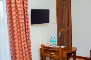 um quarto com uma mesa e uma televisão na parede em Kilimanjaro Crane Hotel em Moshi