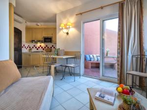 - un salon avec une cuisine et une table avec des chaises dans l'établissement Apartment Cala Rossa 1505 by Interhome, à Trinità d'Agultu e Vignola