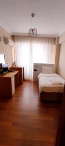 a bedroom with two beds and a desk and a window at MD CITY HOTEL in Canakkale