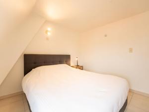 1 dormitorio con 1 cama blanca en el ático en Apartment Koekoeksnest by Interhome, en De Haan