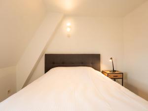 1 dormitorio con 1 cama blanca y 1 lámpara en Apartment Koekoeksnest by Interhome, en De Haan