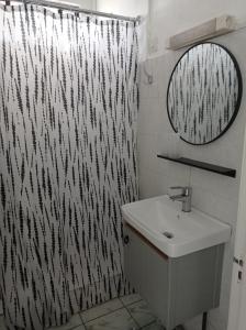 La salle de bains est pourvue d'un rideau de douche noir et blanc et d'un lavabo. dans l'établissement Appartement Cosy, à Beau Bassin-Rose Hill