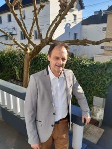 a man in a suit standing next to a fence at Chambre avec douche in Lourdes +2 photos