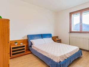 ein Schlafzimmer mit einem blauen Bett und einem Fenster in der Unterkunft Apartment Syria by Interhome in Domaso