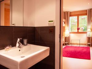 a bathroom with a white sink and a red rug at Chalet Chalet Olivier by Interhome in Villars-sur-Ollon