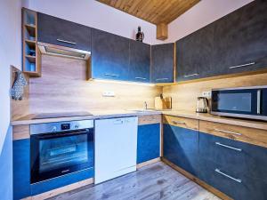 a kitchen with blue cabinets and a microwave at Apartment Pod Černou Studnicí-3 by Interhome in Nova Ves nad Nisou