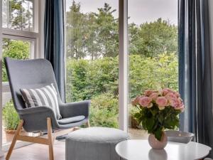 a living room with a chair and a vase of pink roses at Holiday Home Jörgen - all inclusive - 100m from the sea by Interhome in Esbjerg