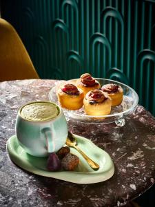 un tavolo con una tazza di caffè e un piatto di ciambelle di Hotel Damier Kortrijk a Courtrai