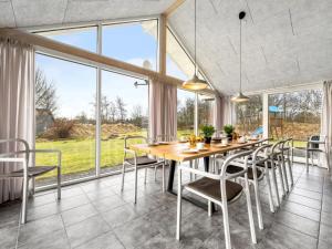 a dining room with a table and chairs and large windows at Holiday Home Talida - all inclusive - 12km from the sea by Interhome in Oksbøl