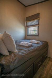 1 dormitorio con 1 cama con 2 almohadas y ventana en 3 Bedroom Waterfront Cottage 15, en Roseneath