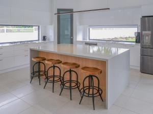 a kitchen with a island with stools and a counter at Amazing House Big Swimming Pool BBQ in Mooloolah