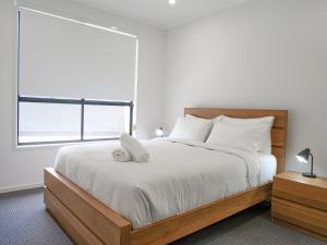 a bedroom with a bed with white sheets and a window at Amazing House Big Swimming Pool BBQ in Mooloolah