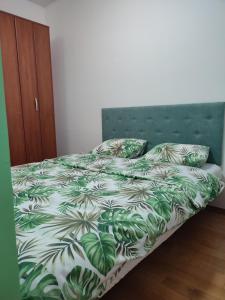 Schlafzimmer mit einem Bett mit einer grünen und weißen Bettdecke in der Unterkunft Studio 33 in Banja Luka