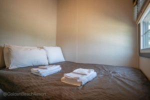 a bed with two towels sitting on top of it at 3 Bedroom Waterfront Cottage 13 in Roseneath