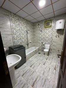 a bathroom with a tub and a toilet and a sink at واحة بكار in Bawiti