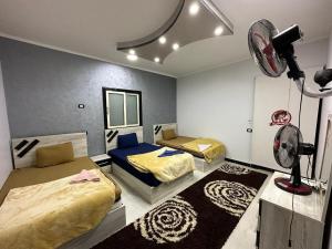 a bedroom with two beds and a fan in it at واحة بكار in Bawiti