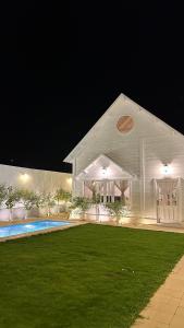 een groot wit huis met een zwembad in de nacht bij شاليهـات موركوت in El Mutainiyat
