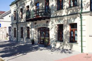 a white building with a balcony on a street at Hotel Akvilon in Suwałki