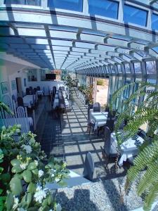 un patio con sillas blancas, mesas y plantas en Hotel Biser, en Pag