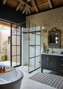 a bathroom with a tub and a sink and a mirror at Ukuthula House in Hectorspruit