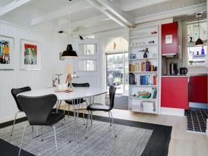 a kitchen with red cabinets and a white table and chairs at Holiday Home Solfrid - all inclusive - 150m from the sea by Interhome in Esbjerg