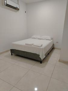 Bett in einem Zimmer mit weißem Boden in der Unterkunft Oasis Olmos in Cereté