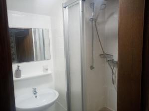 a white bathroom with a sink and a shower at Ferienwohnungen direkt am See mit Einzelnbetten in Waldeck