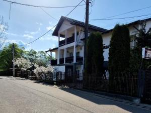 a white house with a fence next to a street at Pensiunea Antonia in Vatra Dornei