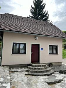 una pequeña casa blanca con una puerta roja en Apartments Jezerce 28, en Jezerce