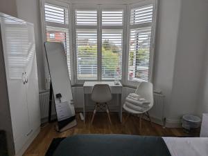 a bedroom with a desk and two chairs and a mirror at Luxury Hotel Rooms in Palmers Green
