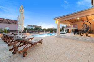 une terrasse avec des chaises longues et une piscine dans l'établissement Villa Kunfin, à Bibinje