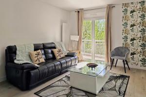 uma sala de estar com um sofá de couro preto e uma mesa de vidro em L'HARMONIE, Appartement 2 chambres proche du lac, calme et lumineux em Annecy