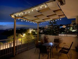 a patio with a table and chairs on a balcony with lights at Waterfront Penthouse in Saronida
