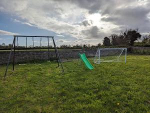 a couple of swings in a field with a goal at Cozy Getaway in Bunratty in Droíchead an Chláir