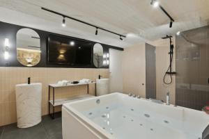 La grande salle de bains est pourvue d'une baignoire et d'une télévision. dans l'établissement KAZA BELLA - Maisons Alfort 5 Luxurious apartment with private garden and Jacuzzi, à Maisons-Alfort