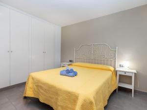 1 dormitorio con 1 cama amarilla y 2 toallas azules. en Apartment Pinos by Interhome, en Port de la Selva