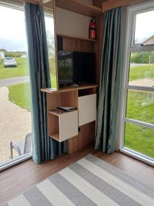 a living room with a tv and large windows at Luxury Pods at Mornest Caravan Park, Anglesey in Gaerwen