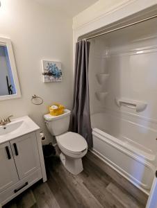 a white bathroom with a toilet and a shower at Newly Renovated 2 Bedroom Beach Front Condo 2A in Lanark