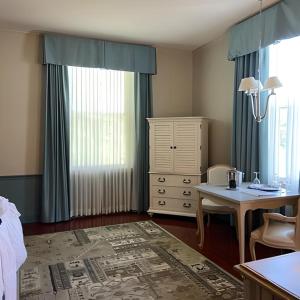 a bedroom with a desk and a table and a dresser at La Tourelle Hotel & Spa in Ithaca