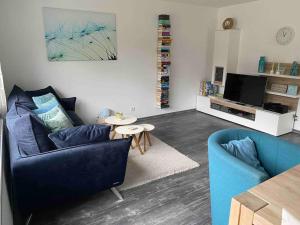 a living room with a blue couch and a table at Fewo Pyramideneiche Detmold/Berlebeck, naturnah in Detmold