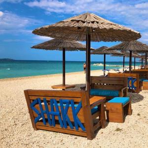 法扎納的住宿－Astraluxe，海滩上的一组椅子和遮阳伞